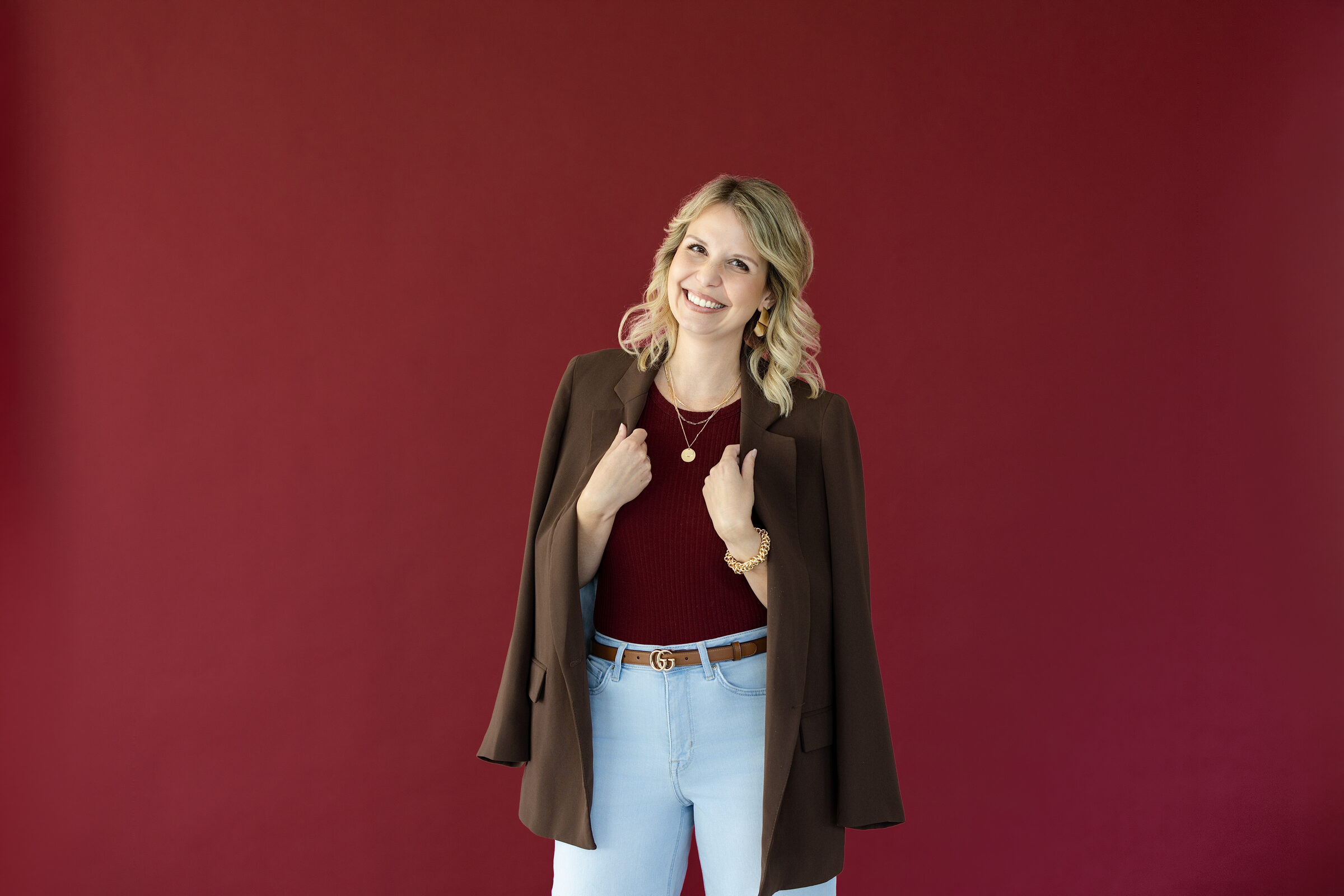 Iris Gassner, Branddesignerin, lächelnd vor bordeauxfarbenem Hintergrund